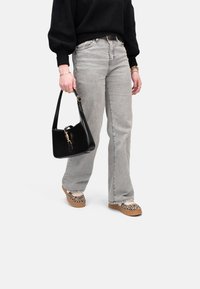 Jeans gris claro con diseño de pierna recta; suéter negro holgado; bolso negro con herrajes dorados; zapatos de plataforma de estampado de leopardo.