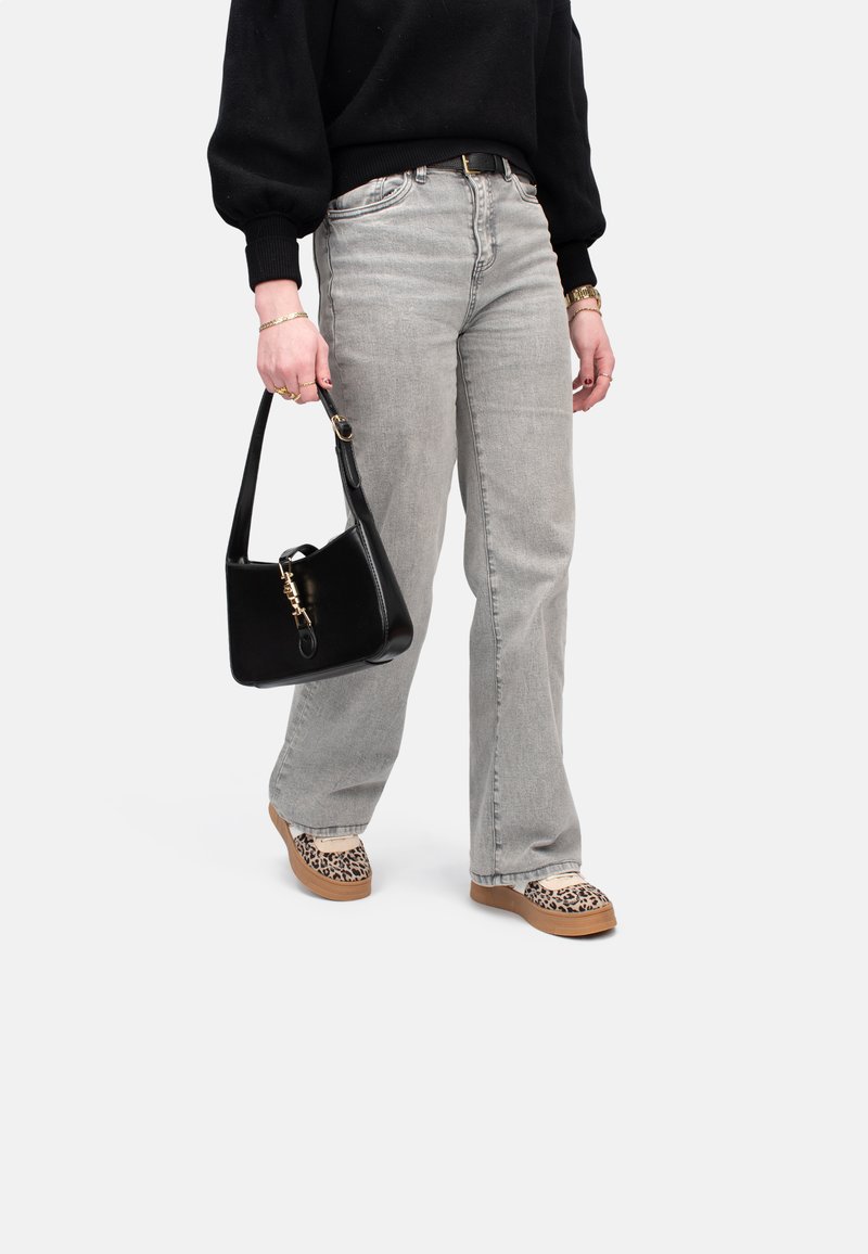 Jeans gris claro con diseño de pierna recta; suéter negro holgado; bolso negro con herrajes dorados; zapatos de plataforma de estampado de leopardo.