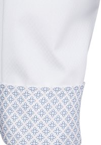 Polsino di camicia bianco con motivo floreale blu, con piccole stelle e punti d'accento, su uno sfondo bianco testurizzato.