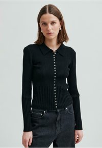 Svart ribbad långärmad cardigan med krage och dekorativ knappframt, med figurnära design och texturerat tyg.