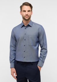 Camicia da uomo con bottoni in tonalità di blu sfumate, realizzata in tessuto intrecciato, con tasca sul petto e bottoni scuri. Vestibilità aderente, maniche lunghe.