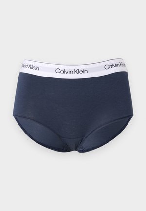 Tumesinised Calvin Kleini naiste püksikud valge elastse vöökohaga, millel on musta kirjaga Calvin Kleini logo.
