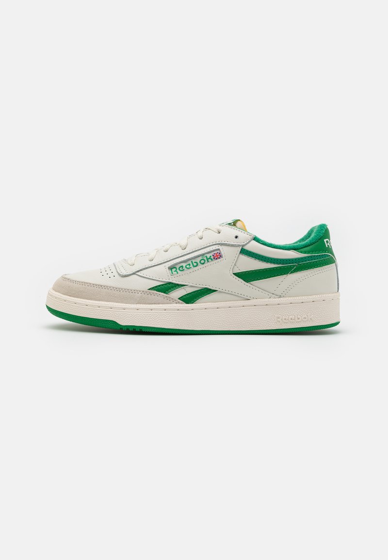 Beli usnjeni teniski čevlji z zelenimi detajli, z teksturiranim podplatom, vezanjem spredaj in Reebok oznako na strani in peti.