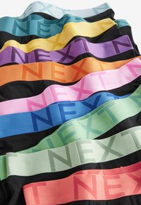 Šareni elastični trakovi s natpisom "NEXT" različitih širina, izrađeni od mekog materijala u nijansama crne, zelene, ružičaste, plave i narančaste.