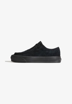 Alacsony szárú fekete velúr sneaker fűzős rögzítéssel, vastag gumi talppal és minimalista dizájnnal, oldalról fehér háttéren.