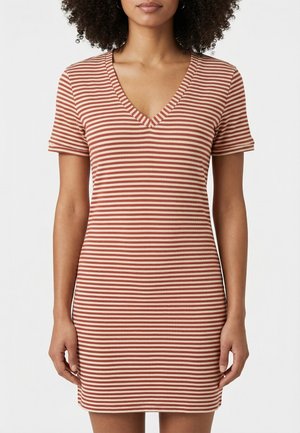 Donna che indossa un vestito aderente a maniche corte con scollo a V, a righe orizzontali beige e ruggine, su sfondo bianco semplice.