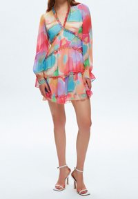Bunt gemustertes Chiffonkleid mit langen Ärmeln, Rüschendetails und ausgestelltem Schnitt. Es zeichnet sich durch lebendige, abstrakte Muster in Pink und Blau aus.