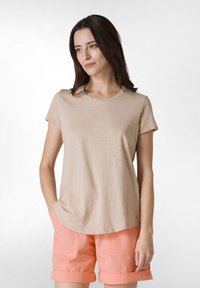 T-shirt beige a maniche corte con scollatura rotonda, abbinato a pantaloni corti color corallo chiaro con risvolti e tasche frontali.