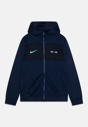 Marineblauwe hoodie met ritssluiting en capuchon, met zwarte panelen, witte "AIR" tekst en een groene Nike swoosh. Gemaakt van zacht, sportief materiaal.