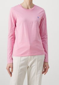 Långärmad rosa t-shirt i bomull med rund halsringning, med en liten blå logotyp på bröstet och en mjuk yta.