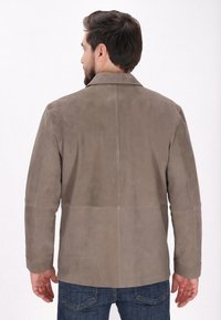 Braune Wildlederjacke mit kragenlosem Hals, nahtlosem Design und langen Ärmeln. Sichtbare Nähte und gerader Schnitt am Saum.