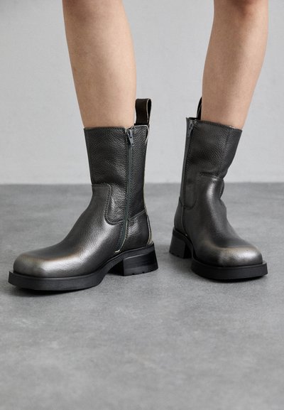 Stivali in pelle alla caviglia grigio scuro con zip laterali, finitura texturizzata, punta rotonda e tacco spesso nero. Eccezionalmente rifiniti con un inserto per il richiamo.