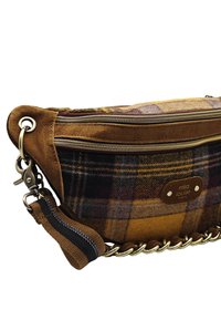 Sac en bandoulière en tissu écossais marron et jaune avec des accents en suède, des double zips dorés et une bandoulière en métal avec une boucle en tissu.