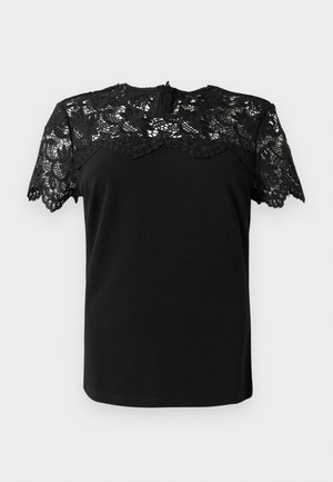 Blouse noire à manches courtes, en dentelle noire délicate avec un bord festonné et un corps noir uni. Fermeture éclair au dos.
