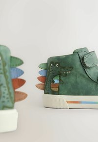 Rohelised nahast kingad krokodillinahast mustriga. Neil on värvikad kangast piigid ja takjakinnitus, tekstuuriga valge kummist tallaosaga.