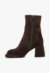 Hnědé semišové kotníkové boty s masivním podpatkem, boční zipovou uzávěrkou a prošíváním nahoře. Hladký povrch, kulatá špička.