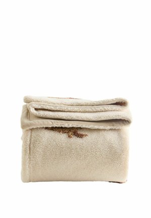 Couverture polaire beige pliée avec une surface douce et texturée et un motif marron subtil sur fond blanc.