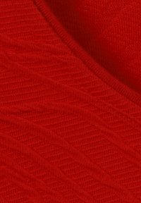 Close-up of red fabric with visible knit texture and seam running diagonally across the surface.