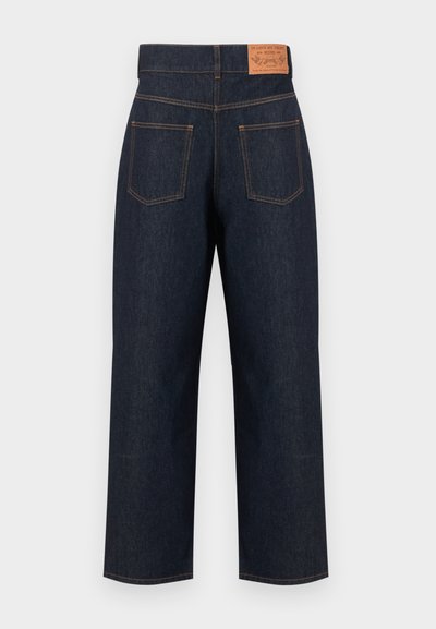 Jean droit bleu foncé avec étiquette patch à l'arrière et deux poches arrière avec surpiqûres orange.