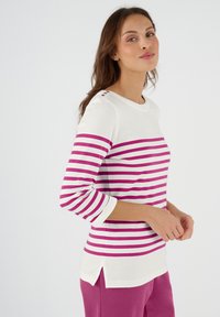 Gestreepte langemouwen top in wit en fuchsia, met een ronde halslijn, driekwart mouwen en knoopdetails op de schouder.
