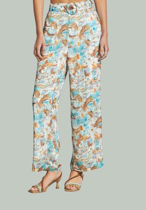 Pantalons à jambes larges légers à motif floral en bleu, marron et crème, avec une taille ceinturée et une texture lisse. Associés à des talons à lanières.