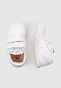 Zapatillas de cuero blancas con dos correas de velcro, punteras redondas y suelas de goma texturizadas; logotipo en la lengüeta y en el lateral.