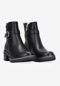 Stivali alla caviglia in pelle nera con finitura texture, dotati di chiusura a zip laterale, cintura regolabile con fibbia e tacco a blocco con suola in gomma.