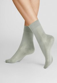 Light green ankle socks made of a smooth, slightly shiny material, featuring a solid color and a simple, seamless design.