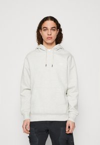Felpa con cappuccio grigio chiaro realizzata in tessuto morbido, con tasca frontale a marsupio, cappuccio con coulisse e polsini a costine. Dettaglio di branding minimale.