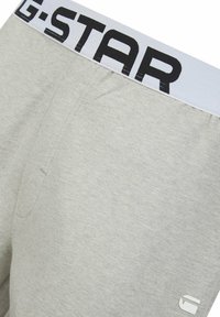 Grijze katoenen boxershorts met een brede elastische tailleband waarop "G-STAR" in grote zwarte letters staat. Glad van textuur met minimale stikseldetails.