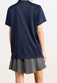 Mörkblå kortärmad topp med randig textur, kombinerad med en grå plisserad kjol. Båda plaggen har mjuk kvalitet och en avslappnad design.