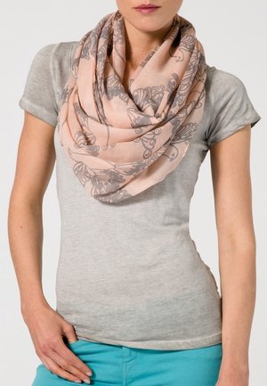 Écharpe légère corail à motif floral, portée en boucle. Texture douce, semi-transparente, elle complète un haut gris et un bas turquoise.