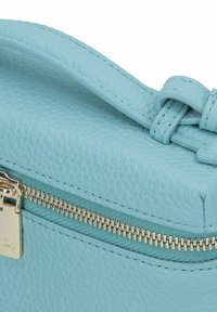Sac en cuir bleu clair avec une surface texturée, doté d'une fermeture éclair dorée et d'un détail de sangle nouée. Le curseur de la fermeture éclaire affiche un emblème de la marque.