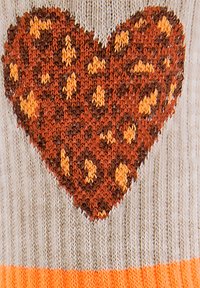 Strickpullover mit einem großen Herzmuster in Braun und Orange auf einem beigen Hintergrund, mit einem orangefarbenen Bund am unteren Ende.