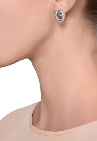 Sølvøreringe med en sammenflettet design, der har klare detaljer. Glat overflade, oval form og poleret finish.