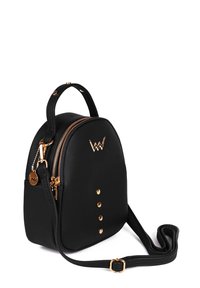 Black faux leather backpack with gold zippers, round shape, front studs, top handle, and adjustable strap. Logo accent on the front.