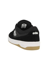 Black and gray sneaker made of suede and mesh, featuring a white rubber sole and a tan outsole, with logo on the side and padded collar.