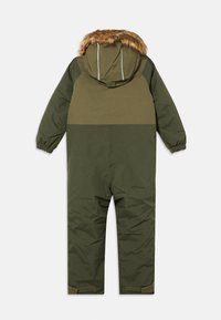 Zaļa polsterēta kombinezona, kas piedāvā ar kažokādu oderētu kapuci, elastīgas aproces un velcro jostas pie potītēm, paredzēta siltumam un aizsardzībai.