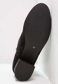 Schwarze Wildleder-Ankle Boots mit strukturierter Sohle, Reißverschluss und Größe 37 auf der Unterseite gedruckt. Glatte Oberfläche und runde Zehenform.