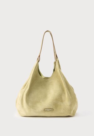 Τσάντα από σουέτ σε ανοιχτό πράσινο, με απαλό υλικό, στρογγυλεμένο σχήμα και λουρί ώμου από δέρμα με διακριτική μεταλλική λογότυπη λεπτομέρεια.