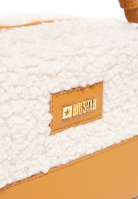 Kremowa górna część o fakturze owczej wełny z brązowym dnem z ekoskóry. Zawiera złote wytłoczone logo "BIG STAR" na brązowej skórzanej łatce.