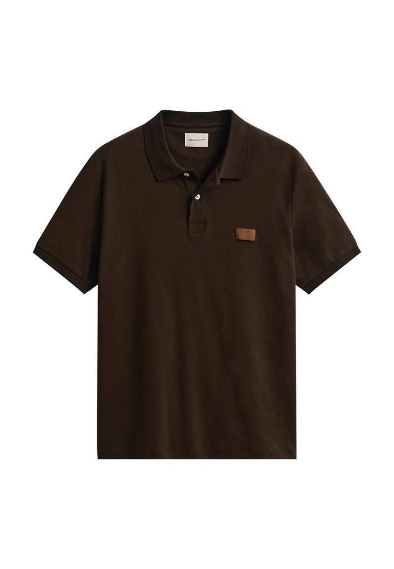 Donkerbruin poloshirt met korte mouwen, twee knopen en een klein rechthoekig leren label aan de linkerborstzijde.