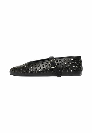 Chaussure plate noire avec une bride Mary Jane, présentant des motifs géométriques découpés et une boucle argentée sur le côté.