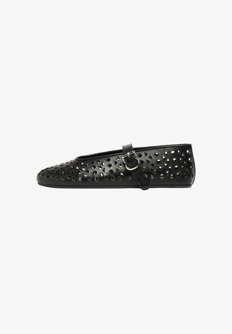 Chaussure plate noire avec une bride Mary Jane, présentant des motifs géométriques découpés et une boucle argentée sur le côté.