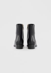 Stivali ankle in pelle nera con finitura liscia, cerniere laterali e tacco basso. Design semplice senza motivi o accenti.