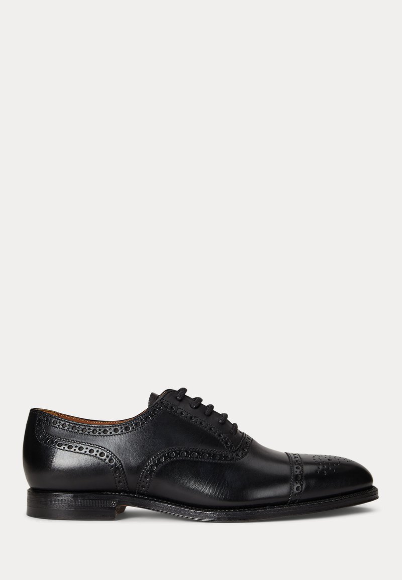 Zapato de vestir masculino de cuero negro con detalles brogue, puntera con tapa y cierre con cordones, mostrado desde el lado exterior sobre un fondo liso.