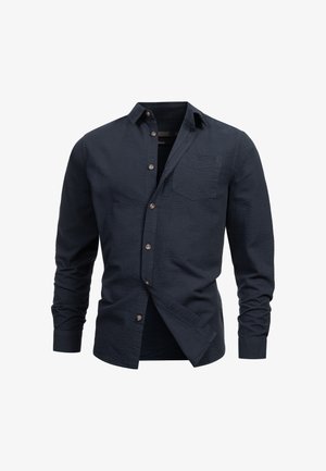 Mornarska košulja dugih rukava s dugim rukavima, strukturiranim materijalom, džepom na prsima i smešnim dugmadi. Prilagođen kroj s ovratnikom.