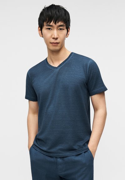 Μπλούζα με κοντά μανίκια και V-λαιμόκοψη σε σκούρο μπλε, κατασκευασμένη από ελαφρύ, υφασμένο ύφασμα. Διαθέτει άνετη γραμμή και διακριτικές οριζόντιες ρίγες.