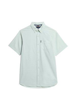 Chemise à manches courtes bleu clair en tissu doux, avec un col boutonné, une poche poitrine et un ourlet arrondi.