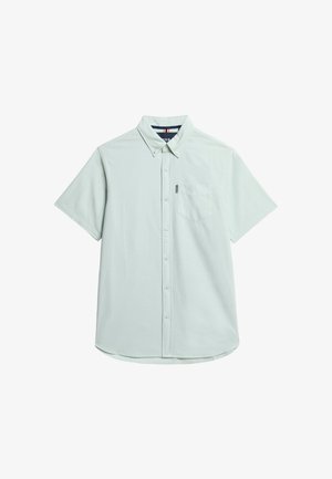 Chemise à manches courtes bleu clair en tissu doux, avec un col boutonné, une poche poitrine et un ourlet arrondi.